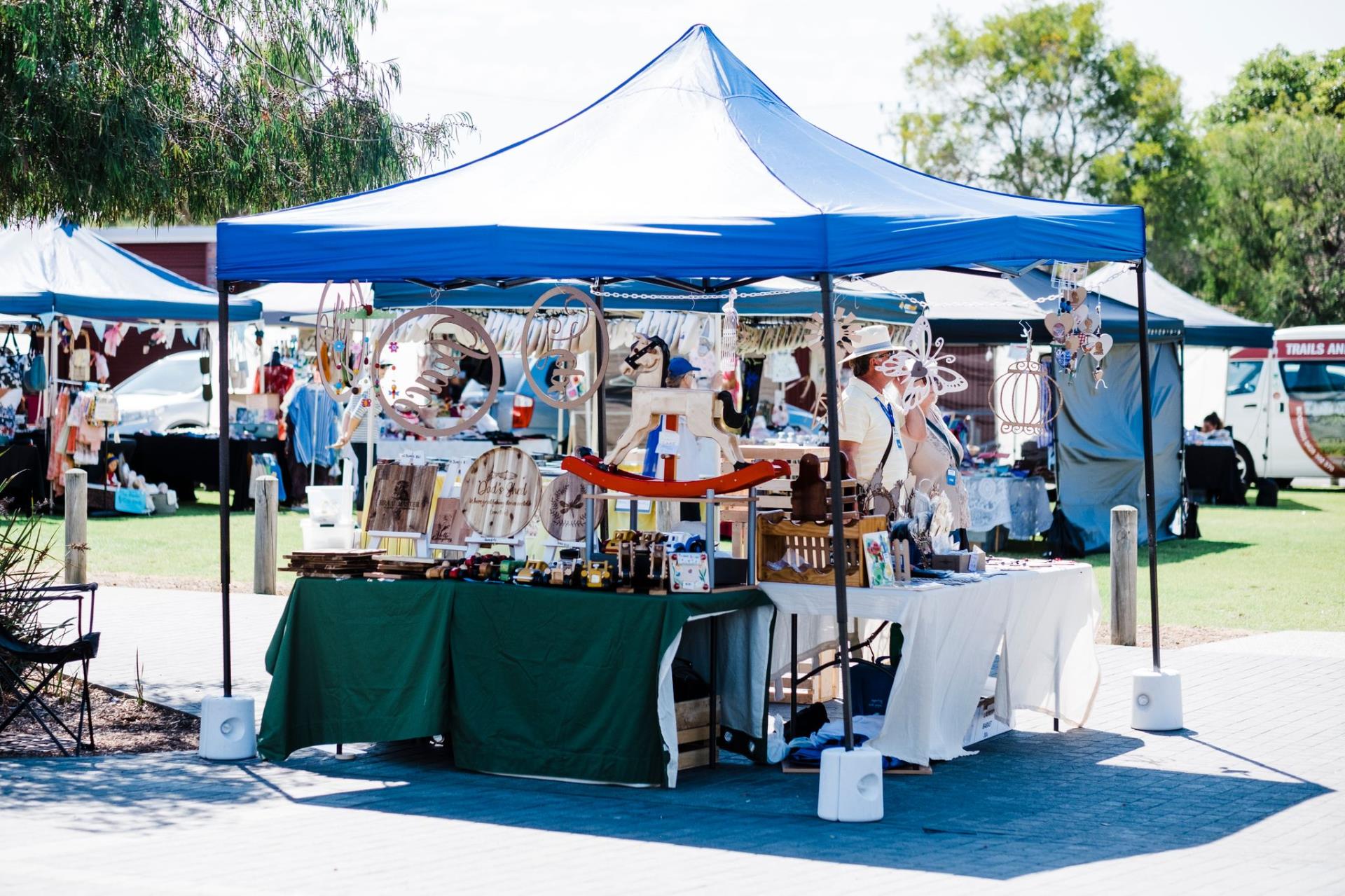 Outdoor market during daylight, under blue marque.